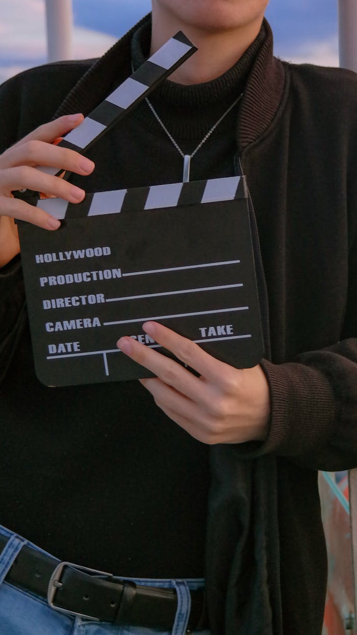 Vertical shot of a person holding a movie clapperboard, symbolizing filmmaking.